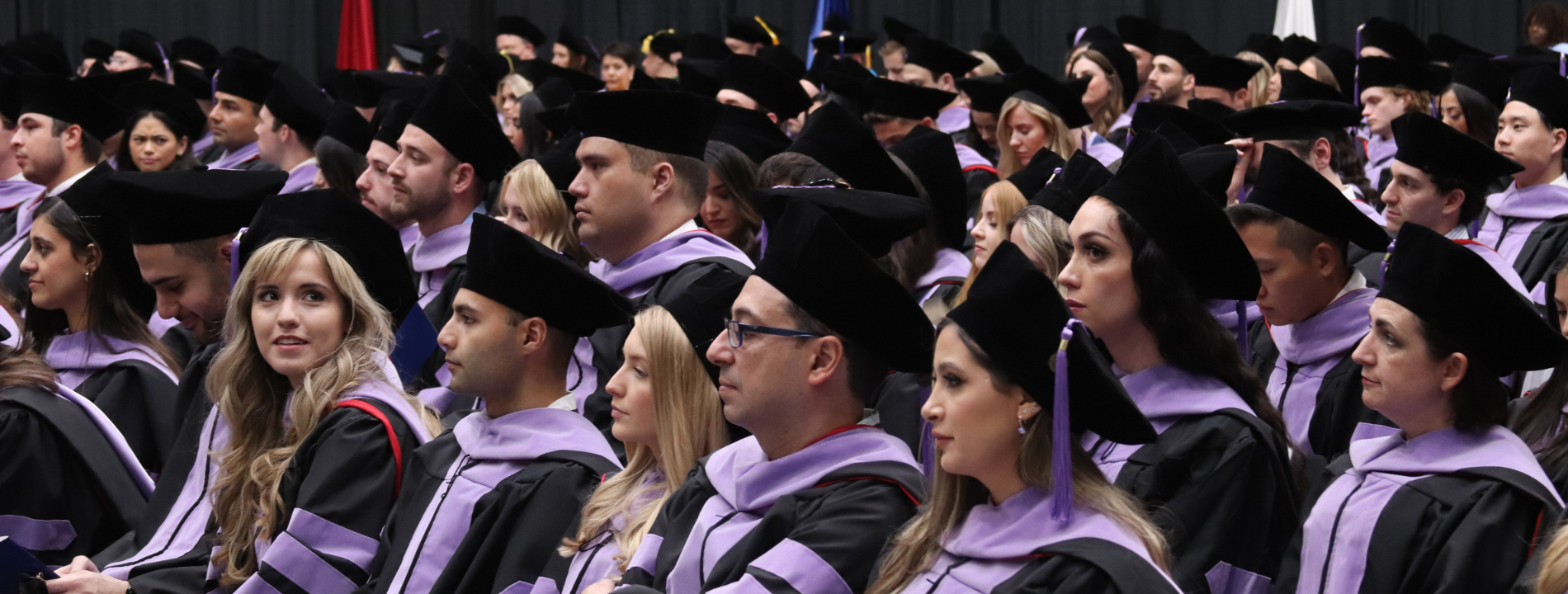 Dozens of graduates seated during a commencement ceremony.